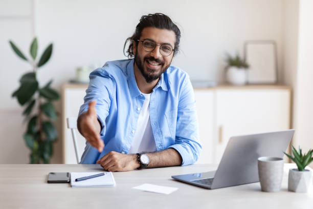 istock Partnership Concept. Smiling Indian Male Entrepreneur Extending Hand For Handshake At Camera 1289179941