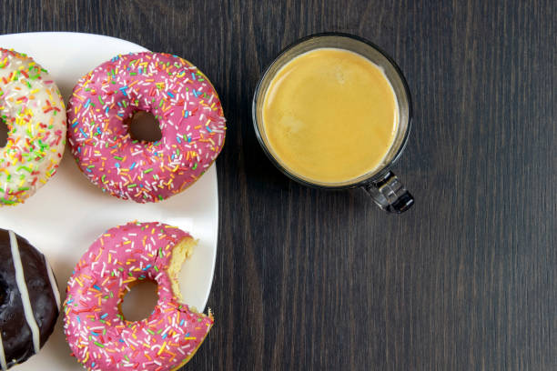 istock Delicious glazed donuts with sprinkling on a wooden table, close up 1289180805