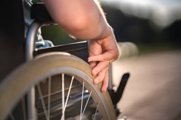 Close up women's hand pushing wheelchair outdoors