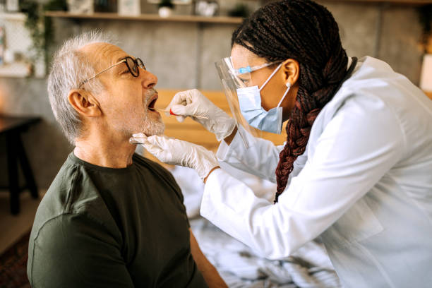 istock Nurse taking swab test from senior man patient during home visit 1289183485