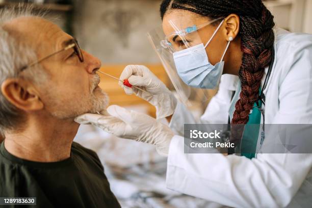 Doctor In A Home Visit To A Senior Man Stock Photo - Download Image Now - Coronavirus, Medical Test, COVID-19