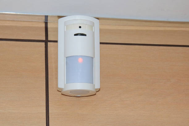 czujnik ruchu systemu alarmowego bezpieczeństwa. biały czujnik głośności wisi na ścianie w pomieszczeniu lub biurze. - motion sensor zdjęcia i obrazy z banku zdjęć