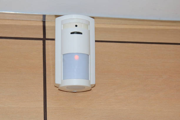 motion sensor of the security alarm system. a white volume sensor hangs on the wall in a room or office. - motion sensor imagens e fotografias de stock