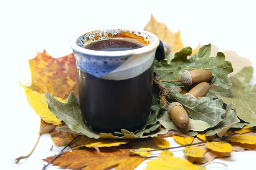 Cup of coffee from roasted acorns on autumn leaves background