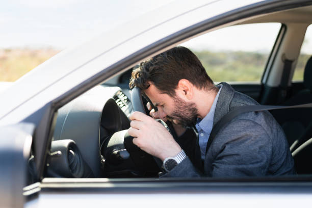 Stressed hispanic man with the forehead on the steering wheel Profile of an adult man looking sad and upset behind the wheel because his car died and has mechanical problems on the middle of the highway stranded stock pictures, royalty-free photos & images