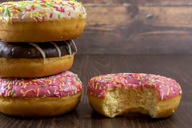 istock Delicious glazed donuts with sprinkling on a wooden table, close up 1289183930