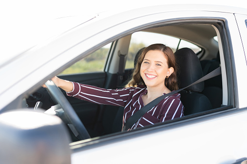 Portrait of an attractive woman in her 20s with a happy face driving on the highway with her seatbelt on