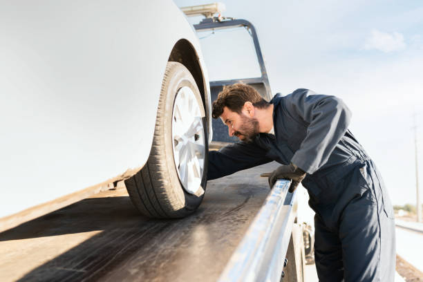 istock Tow truck worker securing the car on the platform 1289186378