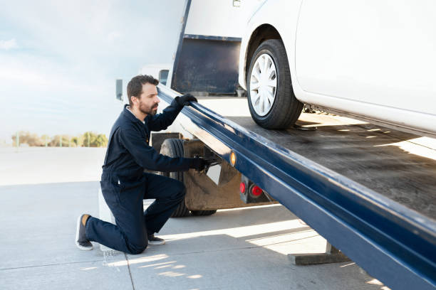 Operator raising the tow truck platform Male tow truck operator placing a dead car in the platform. Worker dealing with a broken-down vehicle on a tow truck engine failure stock pictures, royalty-free photos & images