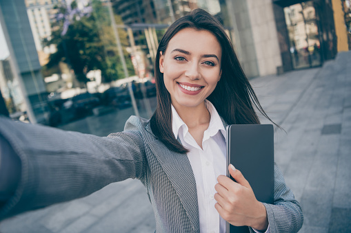 Photo of attractive positive young businesswoman take selfie hold laptop outdoors in downtown city center.