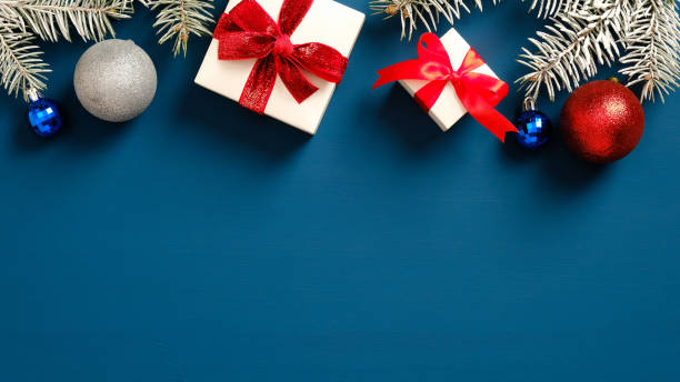 istock Christmas frame border made of gift boxes and pine branches with balls on dark blue background. Flat lay, top view. Christmas postcard template, New year banner mockup. 1289188760