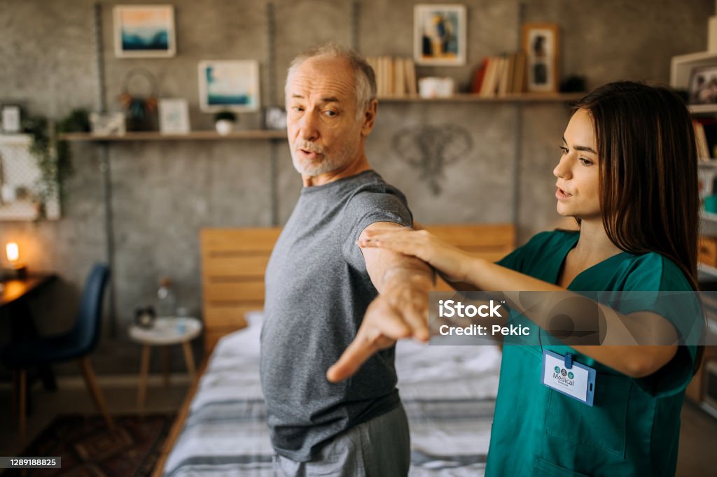 Senior adult man and home healthcare nurse, physical therapist Senior adult, male patient does arm exercises with home healthcare nurse or physical therapist in nursing home or home setting Physical Therapy Stock Photo