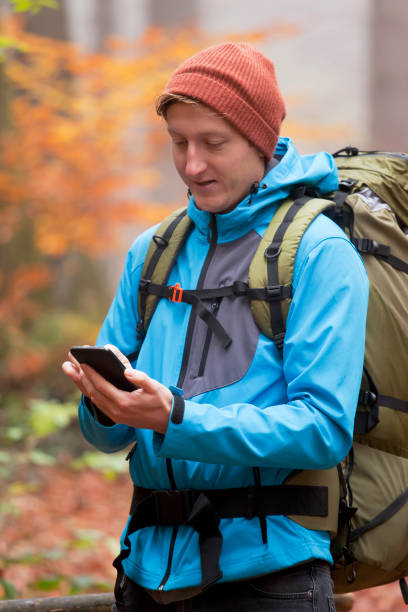 istock Young backpacker looking at smartpone in a colorful forest in autumn 1289189101