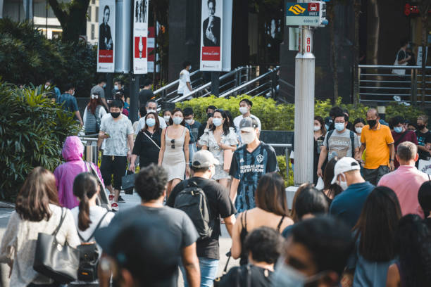 People waiting to cross the Orchard Road in Singapore The Orchard Road crossing in Singapore is one of the busiest in the world, here seen an afternoon during the Covid-19 corona pandemics in October 2020. All people wearing masks to protect themselves. singapore mASK stock pictures, royalty-free photos & images