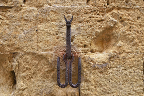 Ancient wrought iron hooks for tying with rope the animals, horses, mules or cattle, on a stone wall. Siena downtown, Tuscany, Italy, Europe. Antique Iron horse hitching