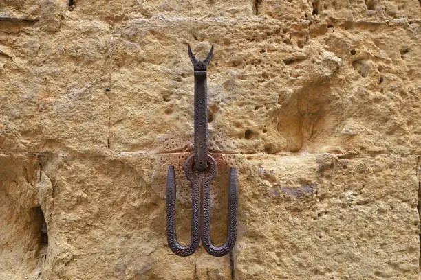 Photo of Old iron hooks embedded in a stone wall, used to leave tethered animals like horses or mules. Siena, Italy