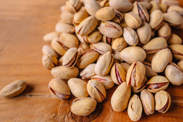 istock Green fresh pistachios as texture on wooden background 1289192587