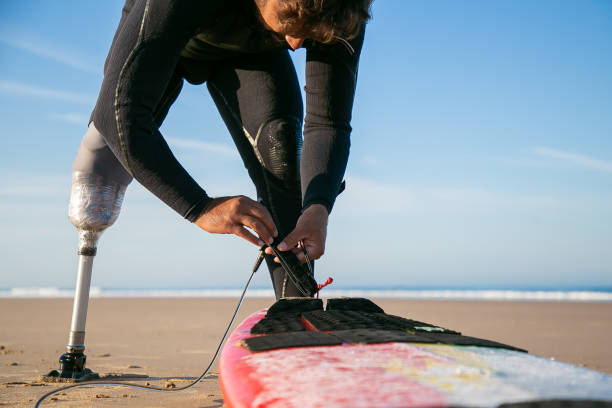 istock Male surfer tying surfboard to his ankle on sand 1289194157