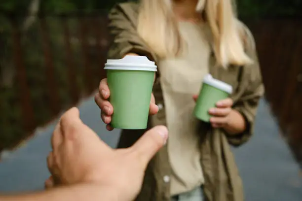 Green paper cup with coffee in woman hand. Time for drink coffee in city. Coffee to go. Enjoy moment, take a break. Disposable paper cup closeup. Delicious hot beverage. Blank space for text, mockup