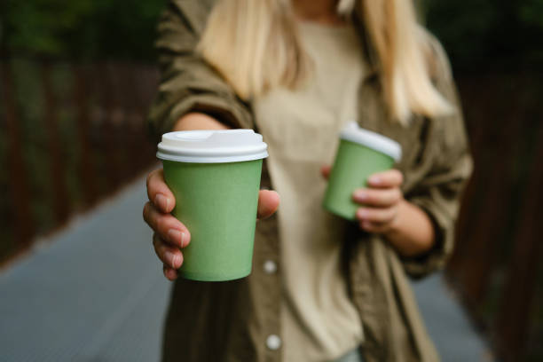 Green paper cup with coffee in woman hand. Time for drink coffee in city. Coffee to go. Enjoy moment, take a break. Disposable paper cup closeup. Delicious hot beverage. Blank space for text, mockup Green paper cup with coffee in woman hand. Time for drink coffee in city. Coffee to go. Enjoy moment, take a break. Disposable paper cup closeup. Delicious hot beverage. Blank space for text, mockup paper coffee cup stock pictures, royalty-free photos & images