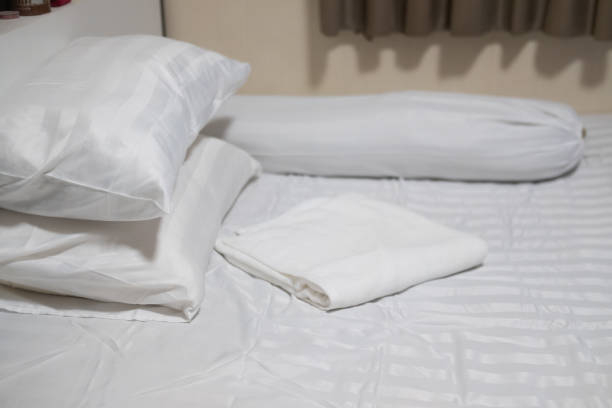 istock Close-up white bedding sheets and pillow with white towel. Fresh bed concept 1289201762