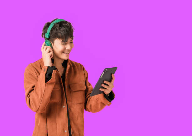 giovane uomo bello asiatico sorridente e ascoltando musica con grandi cuffie verdi - music listening child smiling foto e immagini stock