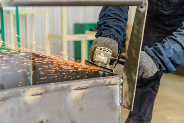 Steel construction worker grinding metal with an angle grinder in factory