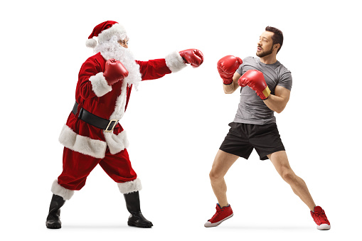 Full length profile shot of a boxer and santa claus fighting with boxing gloves isolated on white background