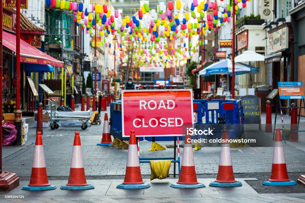 Road closed sign in Chinatown, central London, UK Color image depicting a road closed sign in the heart of Chinatown, London, UK. Focus is on the sign in the foreground, while the shops and restaurants of Chinatown, as well as the colorful lanterns strung across the street, are defocused in the background. Road Closed Sign Stock Photo