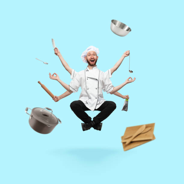 istock Happy handsome multi-armed cooker levitating isolated on blue studio background with equipment 1289205339