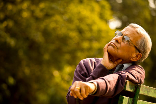 istock Thoughtful senior man sitting at park 1289206696
