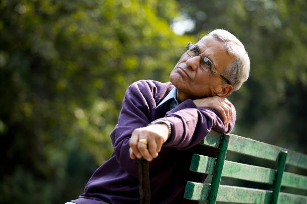 istock Thoughtful senior man sitting at park 1289206728