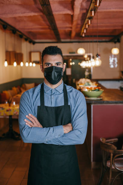 istock African american waiter wearing face mask looking at camera. 1289209188