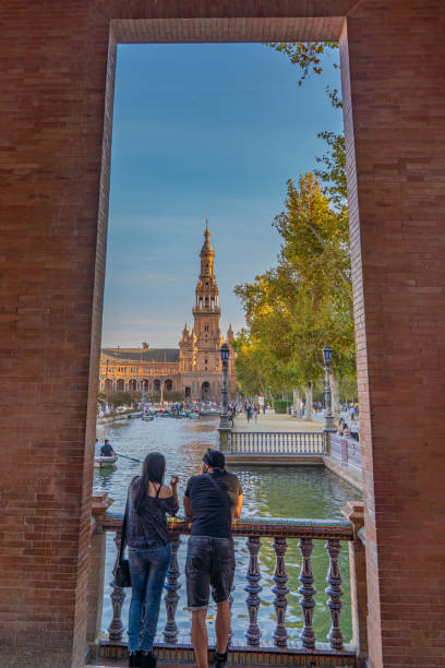 un séjour en couple au canal de plaza de espana espagne square avec des bateaux sur le canal dans le beau centre-ville de séville en espagne - spain plaza de espana europe town square photos et images de collection