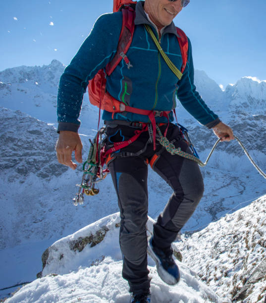 istock Mountaineer climbs up snowy mountain ridge, peaks distant 1289212729