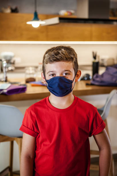 istock Boy with a protective mask in a kitchen at home ready for school. 1289214344