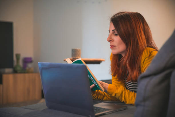istock Young Women at home reading a book on sofa 1289217813