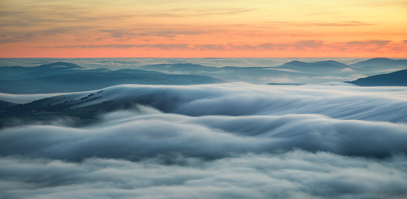 Wavy blankets of thick fog over valleys and hills at sunrise in Triacastela Galicia
