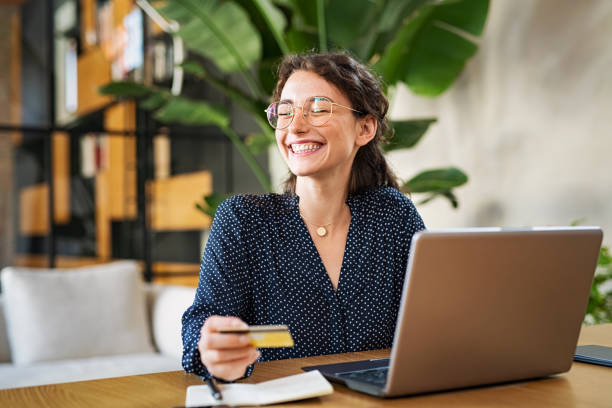 mujer con portátil usando tarjeta de crédito - banca electrónica fotografías e imágenes de stock