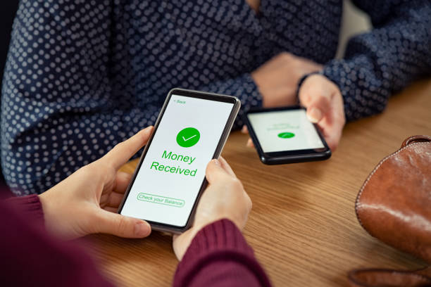 Woman receiving digital money using phone Close up of woman hands holding mobile phone with application to receive money. People holding smart phone and making cashless payment transaction in a shop. Close up of smartphone screen displaying payment sent with money received message. mobile payment stock pictures, royalty-free photos & images