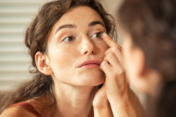 mujer aplicando lente de contacto en el baño - human eye eyesight optometrist lens fotografías e imágenes de stock