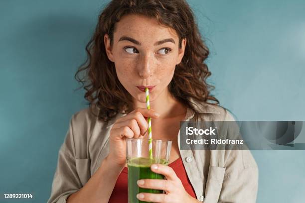 Mujer Joven Bebiendo Jugo Desintoxicato Con Paja En La Pared Azul Foto de stock y más banco de imágenes de Comida sana