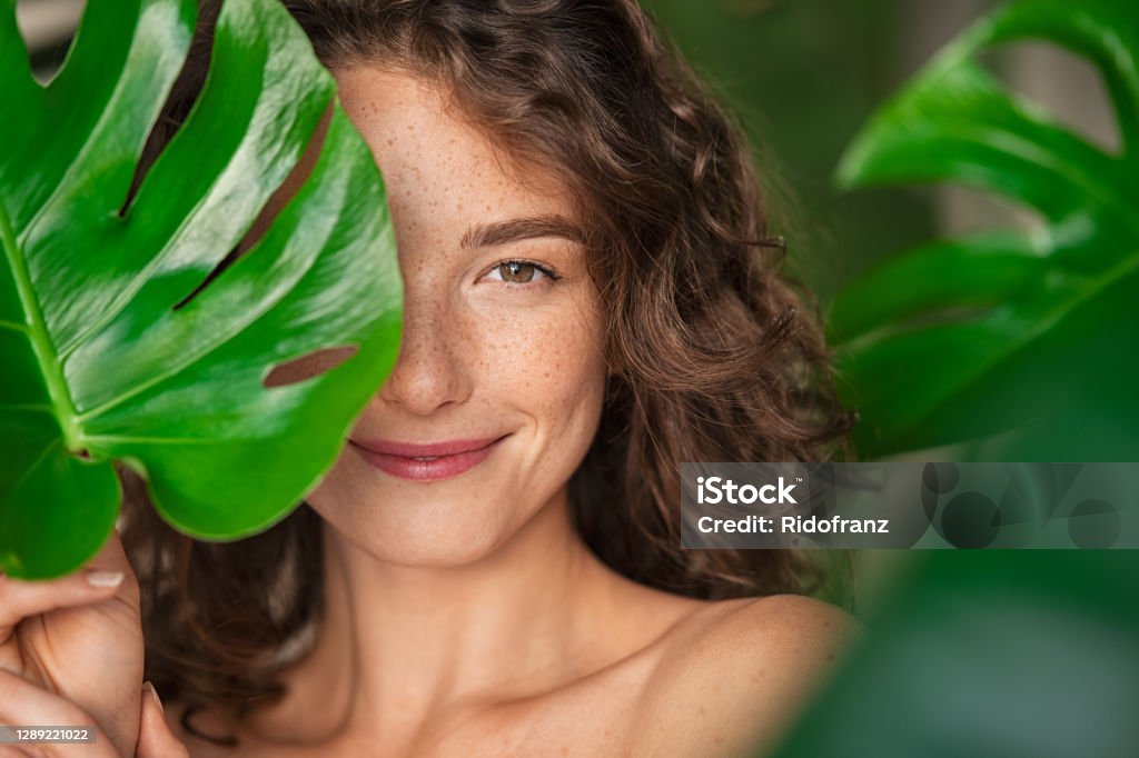 Mulher natural de beleza cobrindo seu rosto com folha tropical - Foto de stock de Mulheres royalty-free