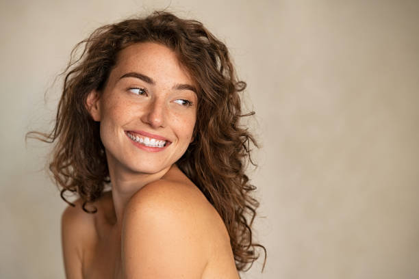 Smiling beauty woman with freckles looking away Portrait of smiling girl enjoying beauty treatment on beige background. Beautiful natural woman looking at copy space, spa and wellness concept. Carefree laughing woman with bare shoulders isolated. human skin photos stock pictures, royalty-free photos & images