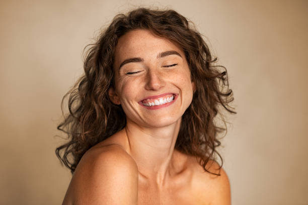 Natural beauty woman laughing with joy Close up of carefree young woman with bare shoulders laughing. Portrait of smiling woman with freckles and closed eyes enjoying beauty treatment. Beautiful girl laughing isolated on background with copy space, skin care and beauty treatment concept. body care and beauty photos stock pictures, royalty-free photos & images