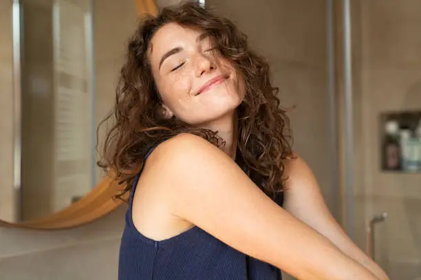 Happy young woman feeling relaxed with eyes closed. Smiling woman stretching with hands forward feeling fresh on a bright morning. Beautiful girl stretch herself in the morning..