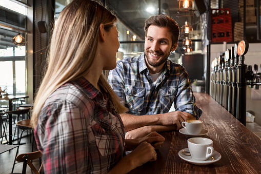 young couple enjoying a cup of coffee while sitting at a counter