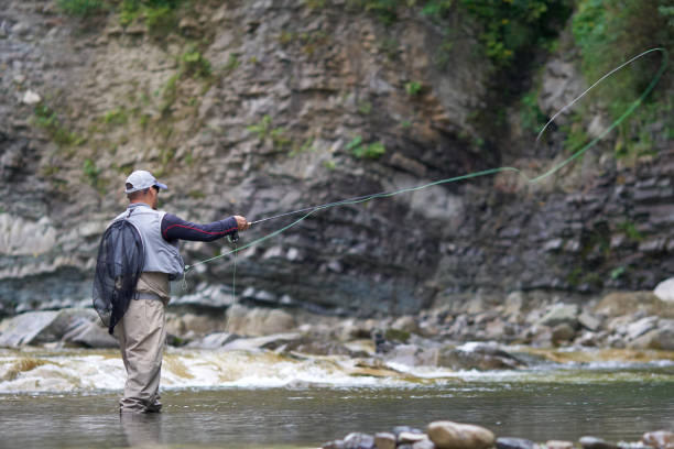 istock Professional fisherman throwing rod into rough river 1289222473