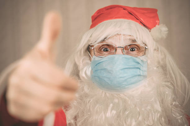 istock Santa Claus with big white beard and protective facemask showing cool gesture Christmas and new year celebration concept 1289222537