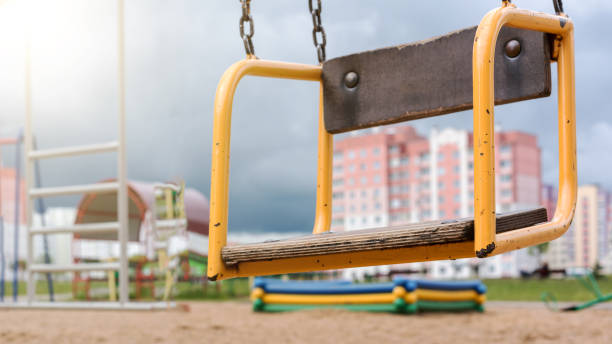 istock orange swing on chains against playground and building 1289222554